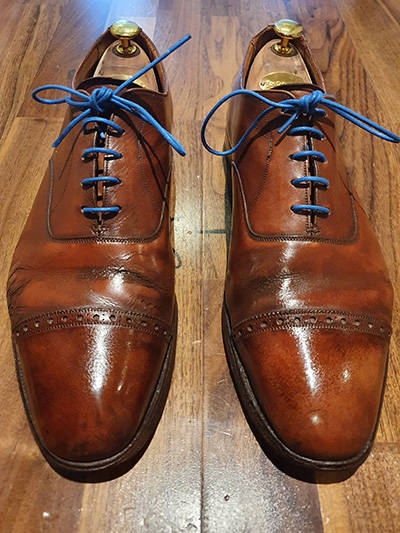 Pair of mens brown shoes with blue laces after a shoeshine